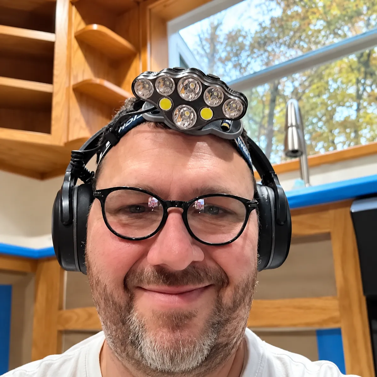 Mike Boyle, owner of Custom Refinishing STL, wearing protective headphones in his woodworking and refinishing workshop.