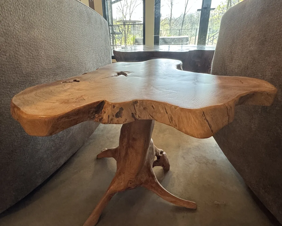 Natural wood live-edge table with sculptural wooden pedestal base, showcasing custom furniture refinishing and wood finishing craftsmanship.