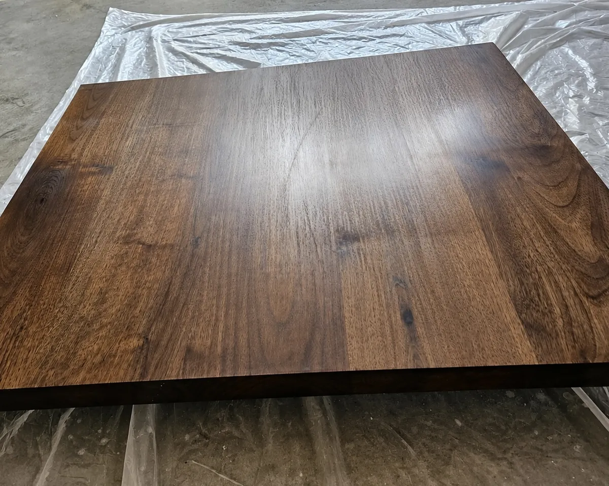 Rectangular wooden tabletop with rich dark brown stain and visible natural wood grain, showcasing custom wood refinishing and staining. 