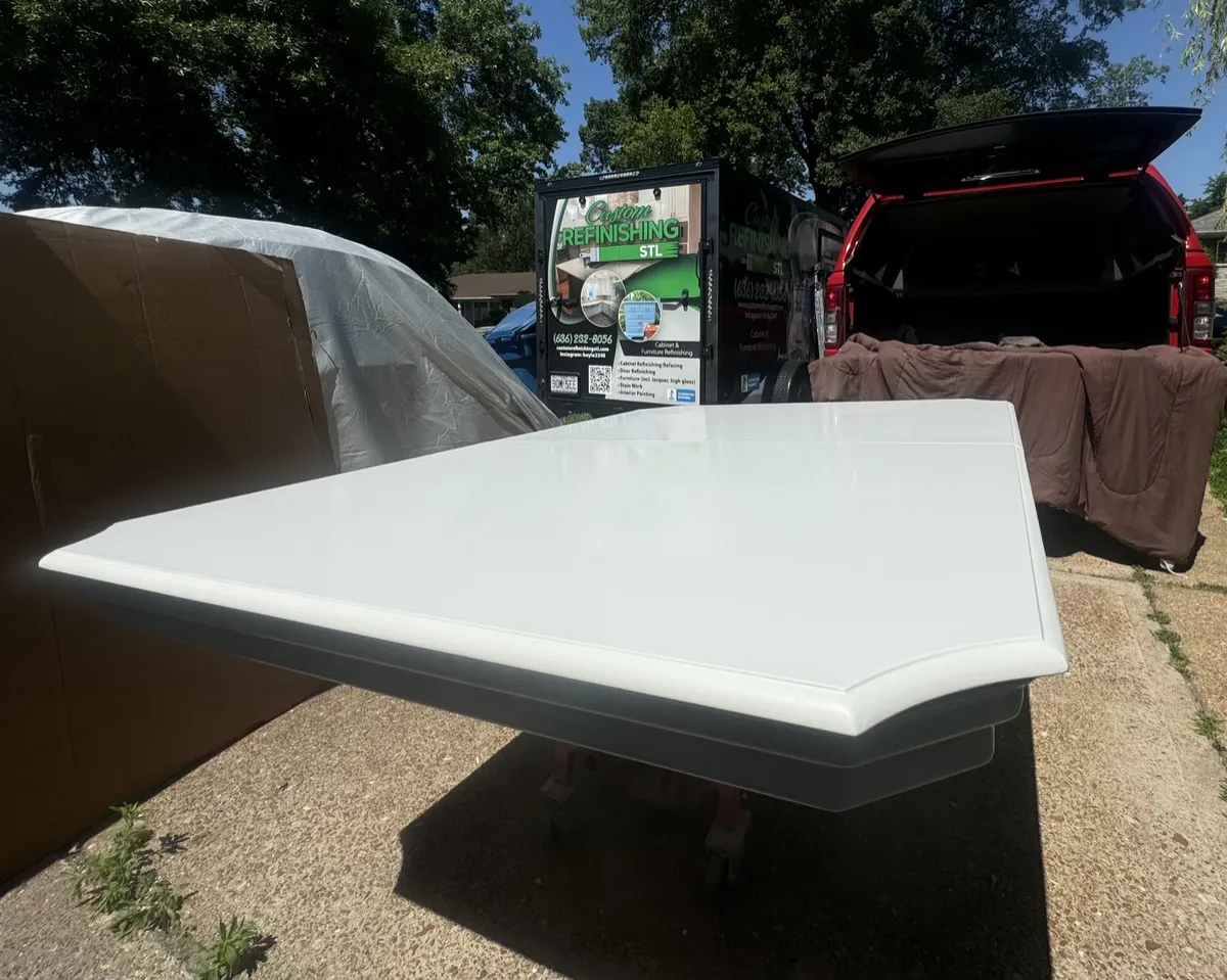 Large white high-gloss refinished tabletop displayed outdoors, showcasing a smooth specialty finish for a custom furniture refinishing project.