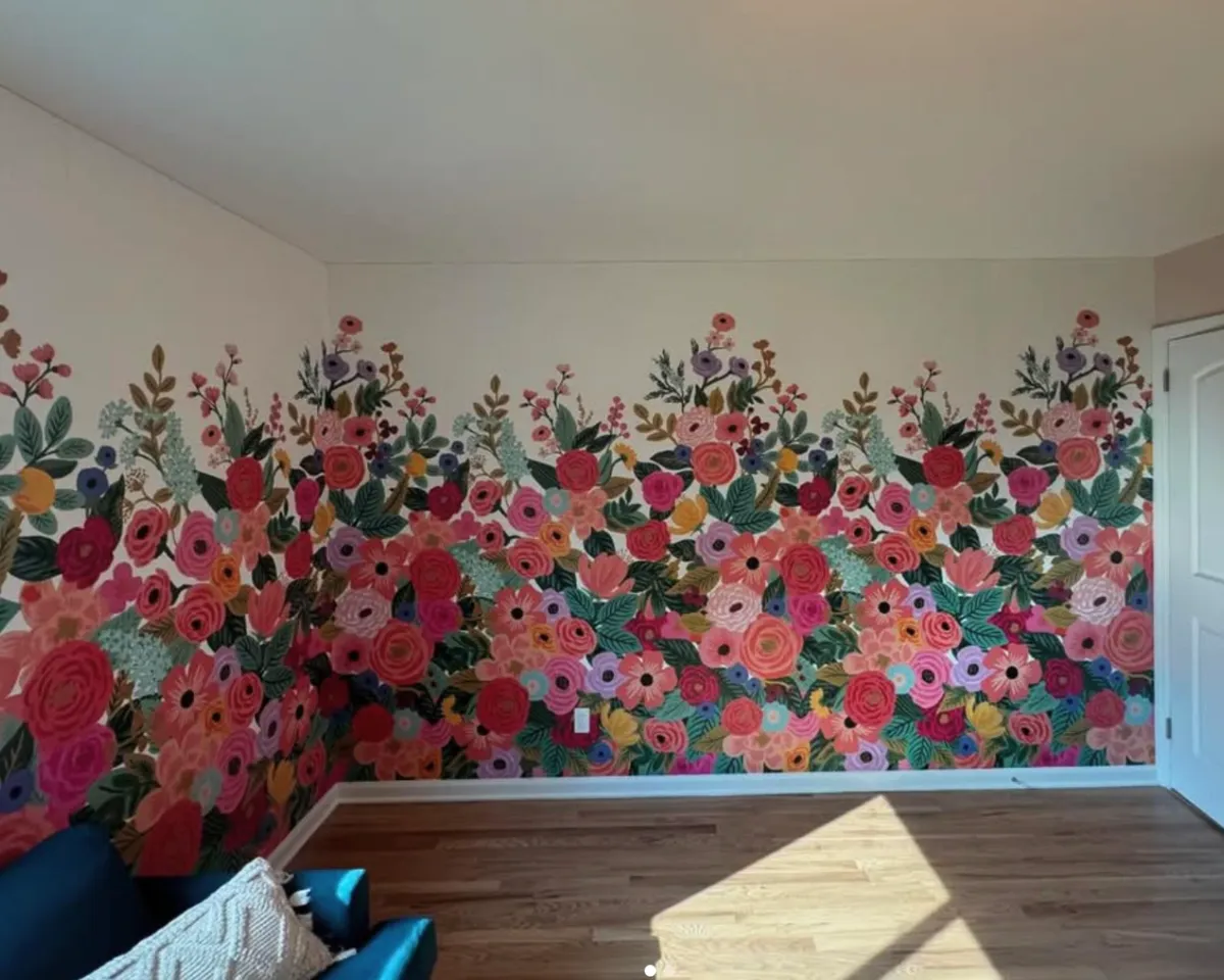 Colorful floral accent wall featuring pink, red, and purple flowers above white trim in a bright residential interior.