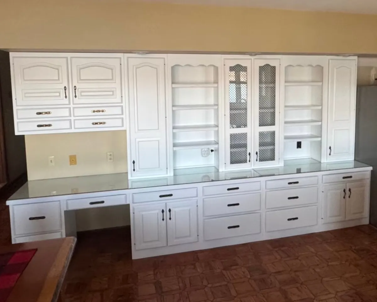 Custom white painted built-in cabinets with drawers, display shelving, glass-front doors, and detailed woodwork in the St. Louis area.
