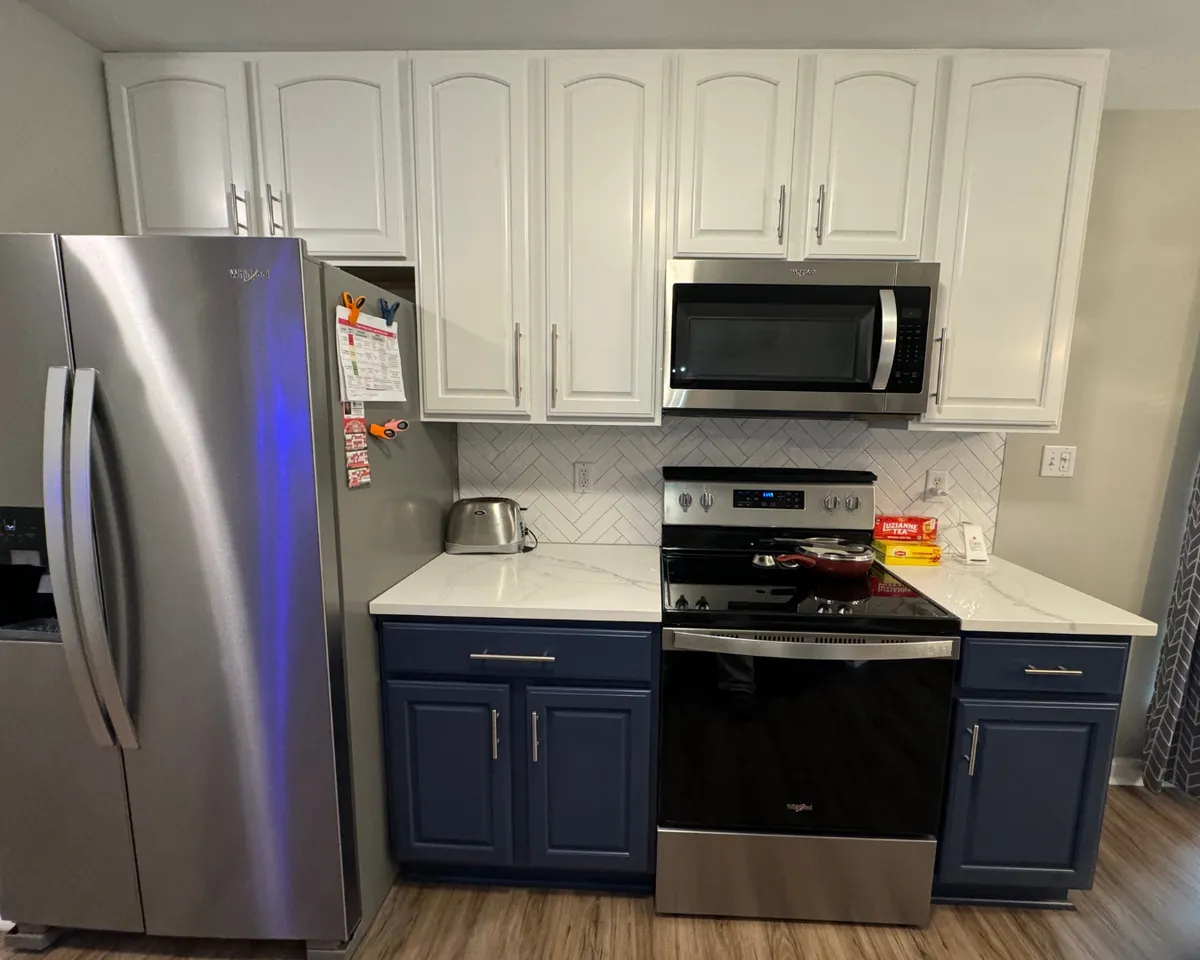 Two-tone kitchen cabinetry featuring white upper cabinets and navy blue lower cabinets with a smooth painted finish in a St. Louis kitchen.