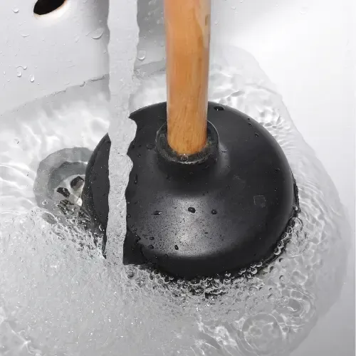 Water running in a clogged sink, with plunger.