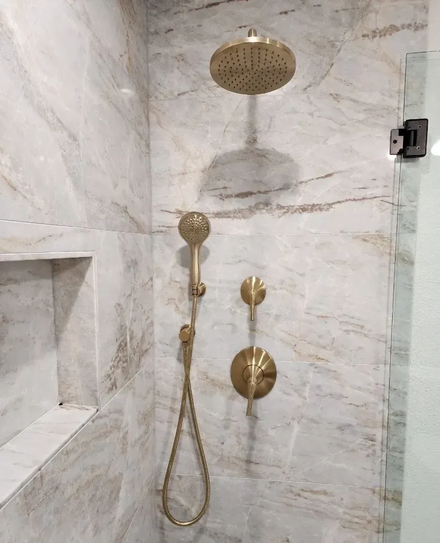 Newly installed marble tiles and gold shower head.