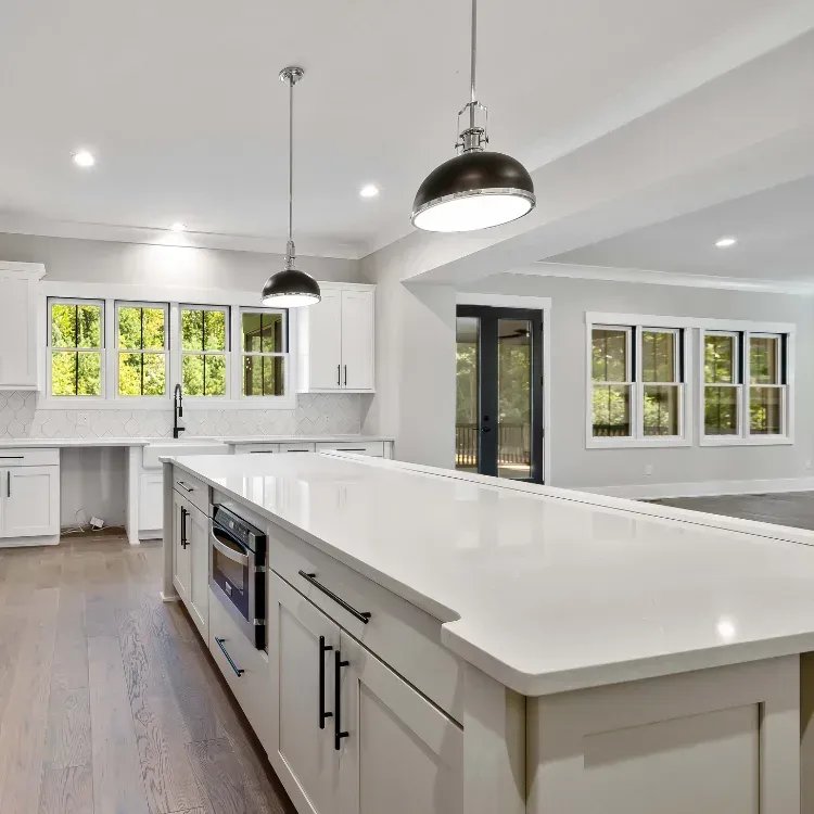 Long kitchen island with white  countertop, and overhead hanging light fixture,