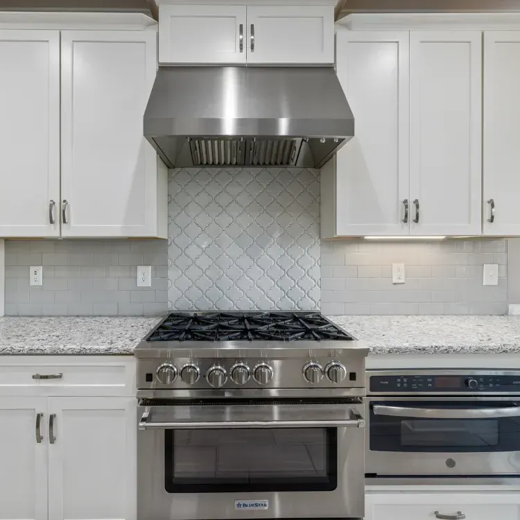 New installed silver kitchen stove under a silver kitchen hood.