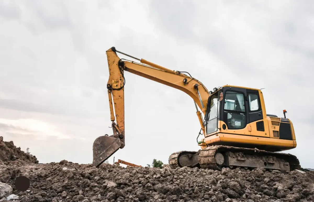 A yellow excavator on a hill of rocks 