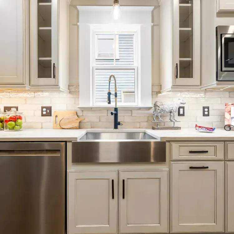 Renovated kitchen sink surrounded by white cabinetry. 