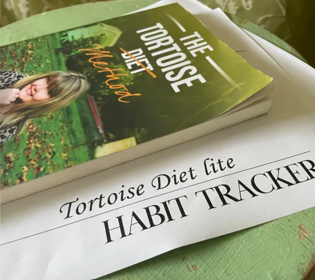 Stack of two printed books, the top one titled 'The Promise Diet Habit Tracker'