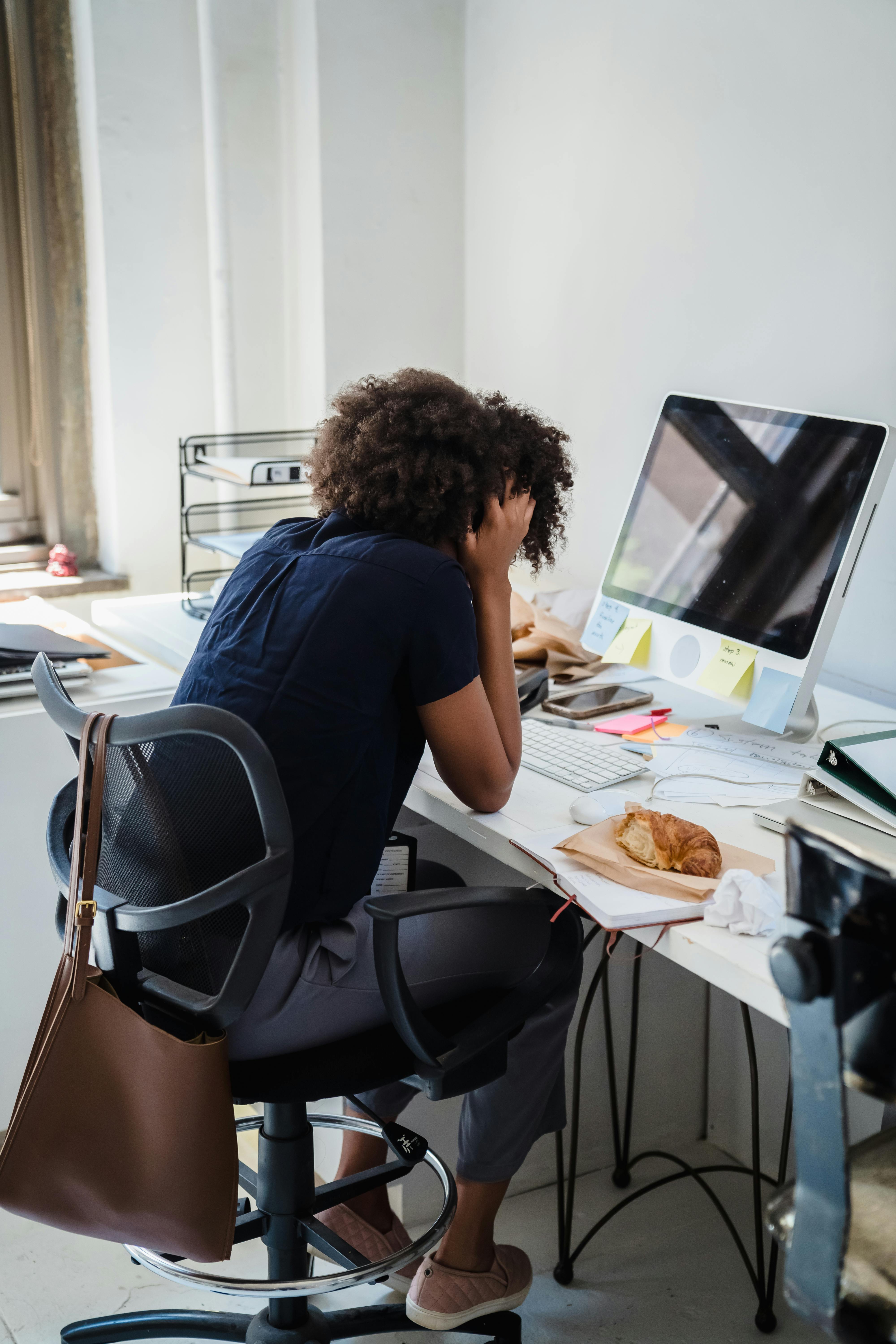 Stressed woman at her desk with mac computer