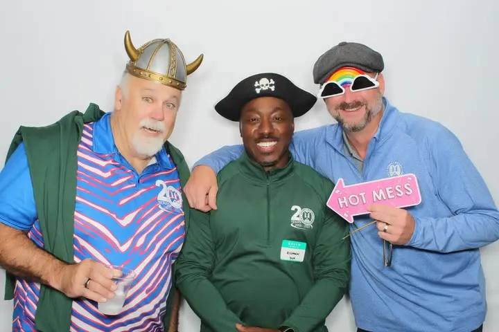 Three guests in hats and props posing at the photo booth