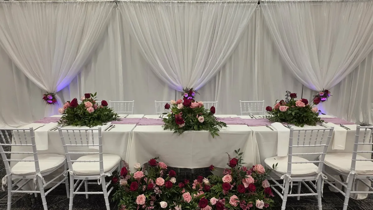 Head table framed by white drapery and uplighting