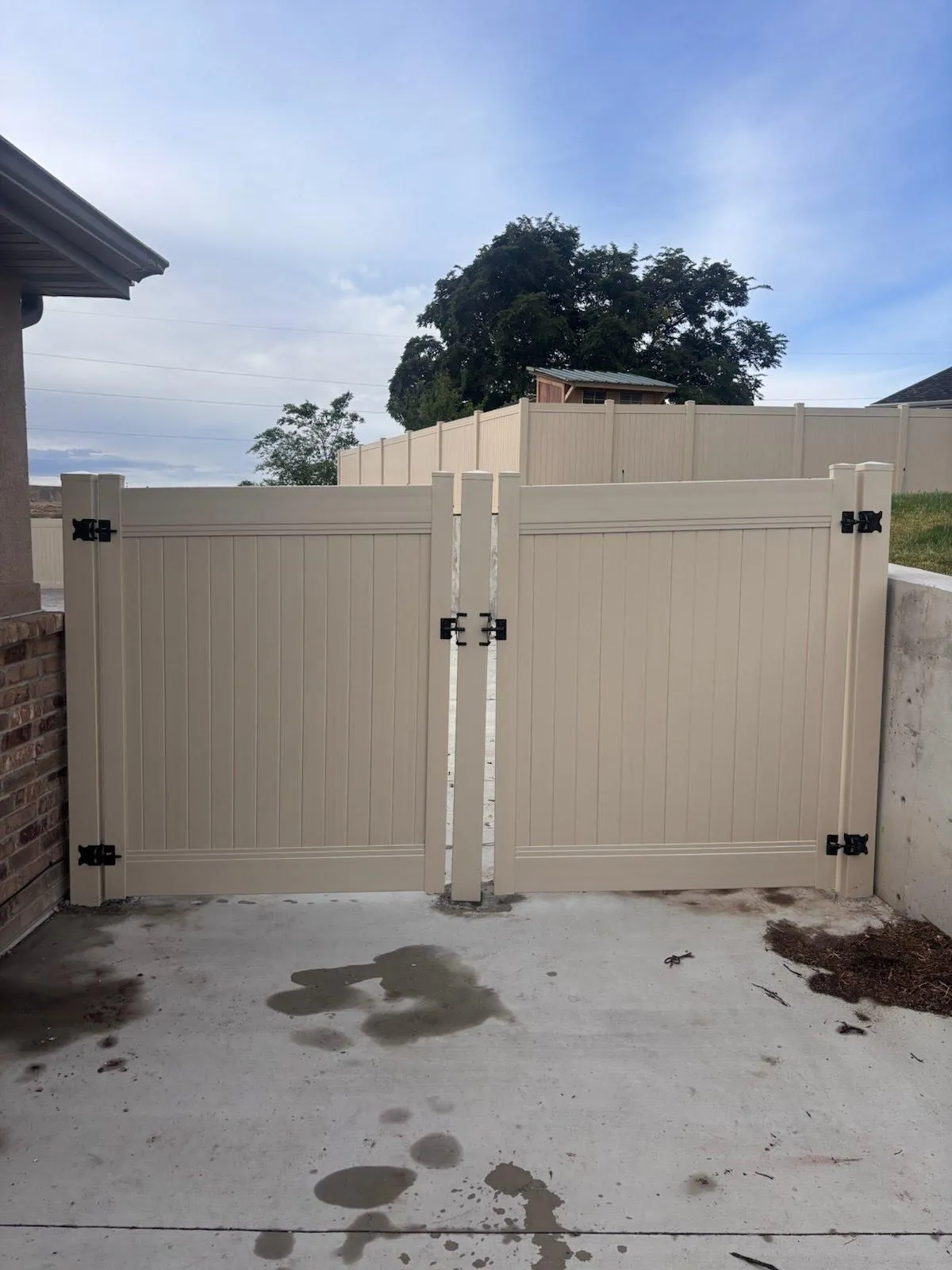 two tan vinyl gates on a concrete driveway