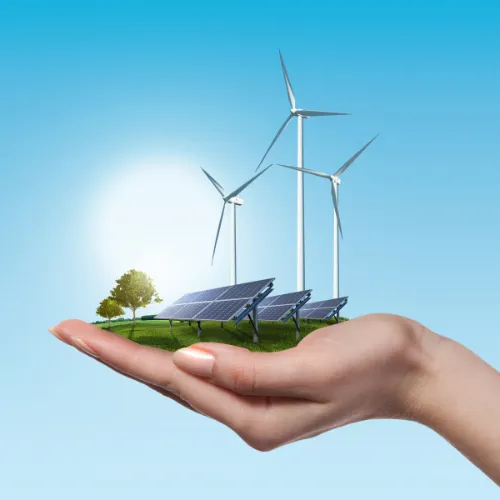 Hand holding a small island with wind turbines and solar panels on it.