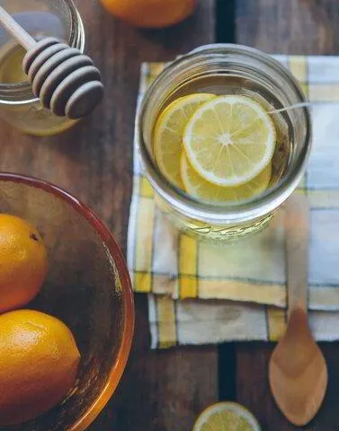 glass of emon water with oranges and honey on a napkin with a wooden spoon