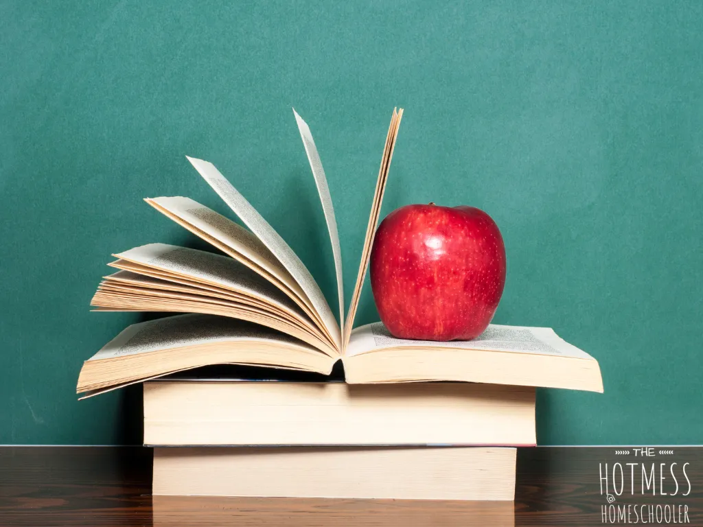 picture of a stack of books, top one open with an apple on top, teal background