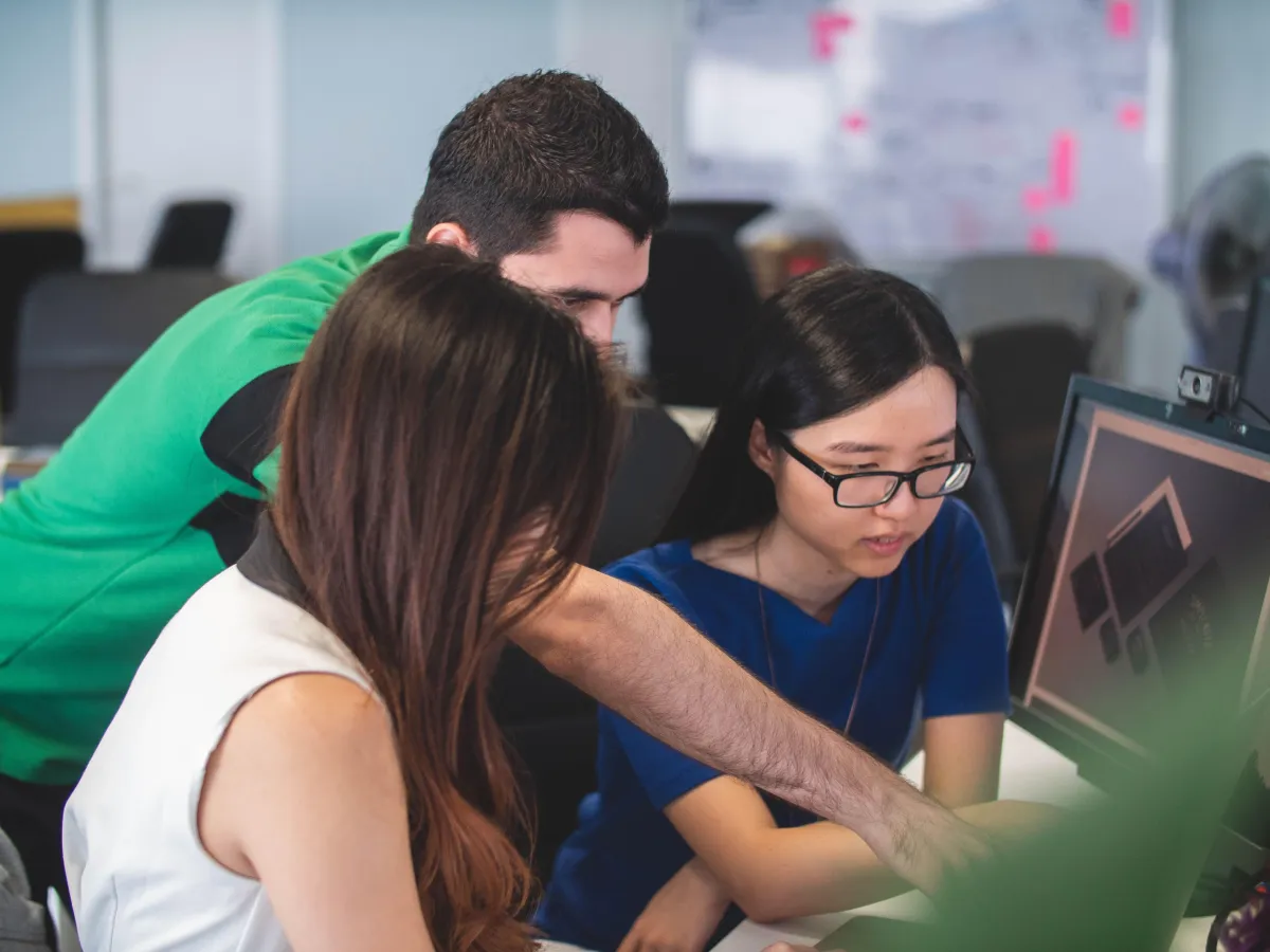 Three people discussing something looking at the desktop screen