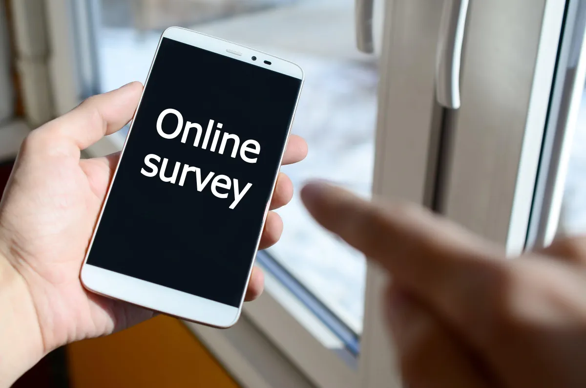 An individual pointing to the phone screen which displays online survey