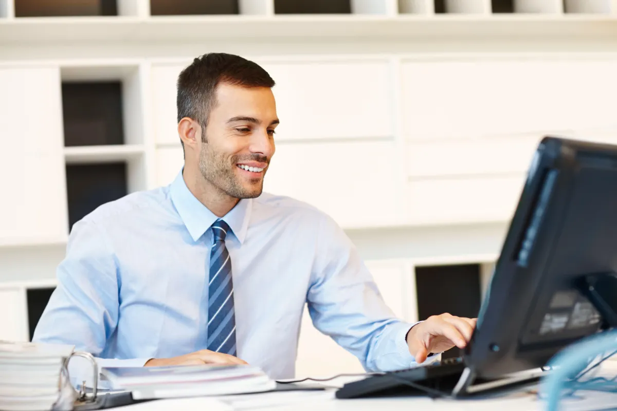 An employee smiling and working on his laptop