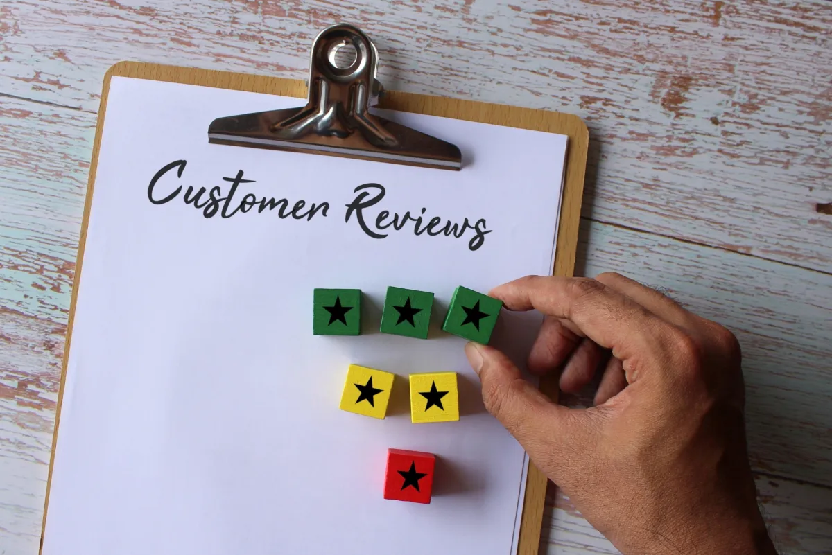 A clipboard is placed on the desk written customer review wooden blocks with stars on top