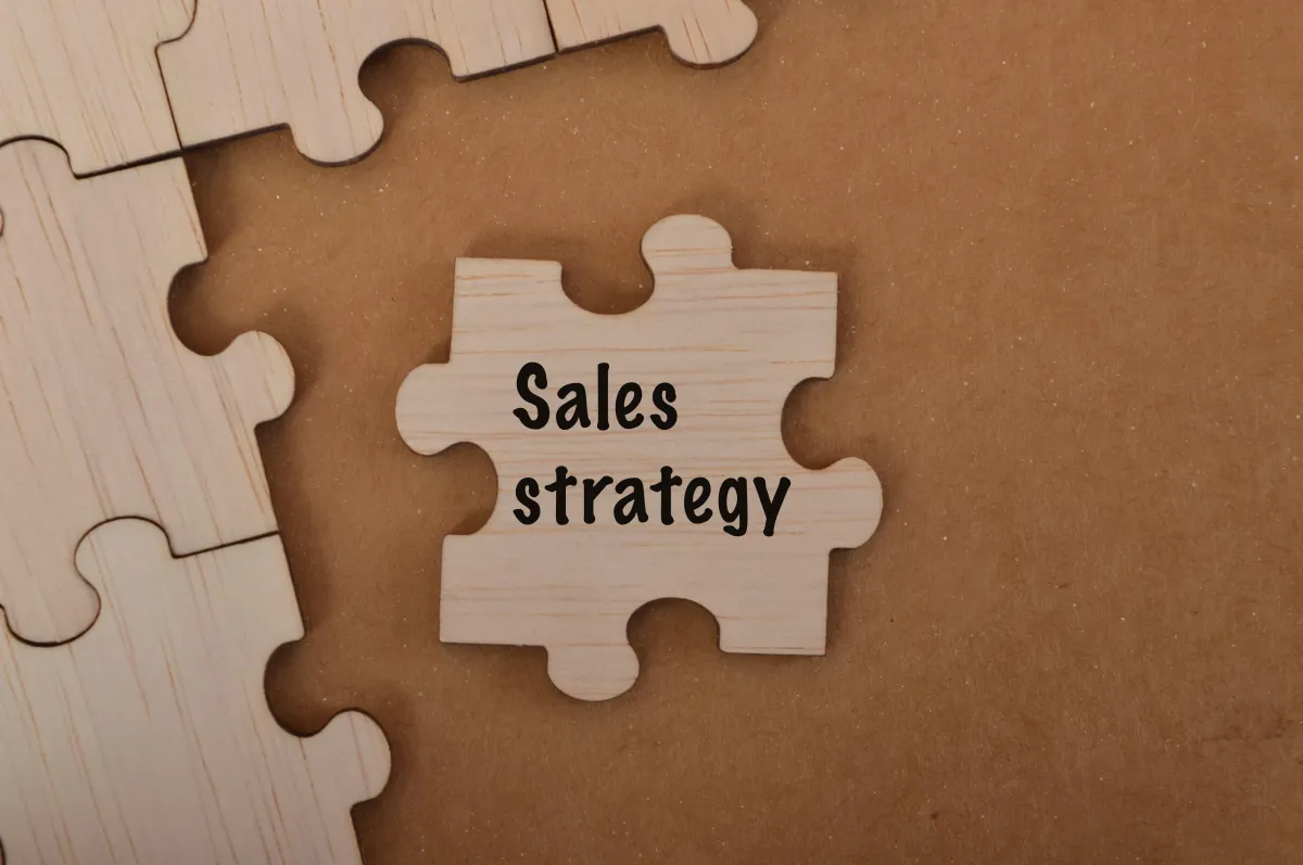 A puzzle piece with the word sales strategy is placed on the desk