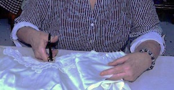 Careful hands gently smoothing out a precious piece of fabric, demonstrating high trust and care.