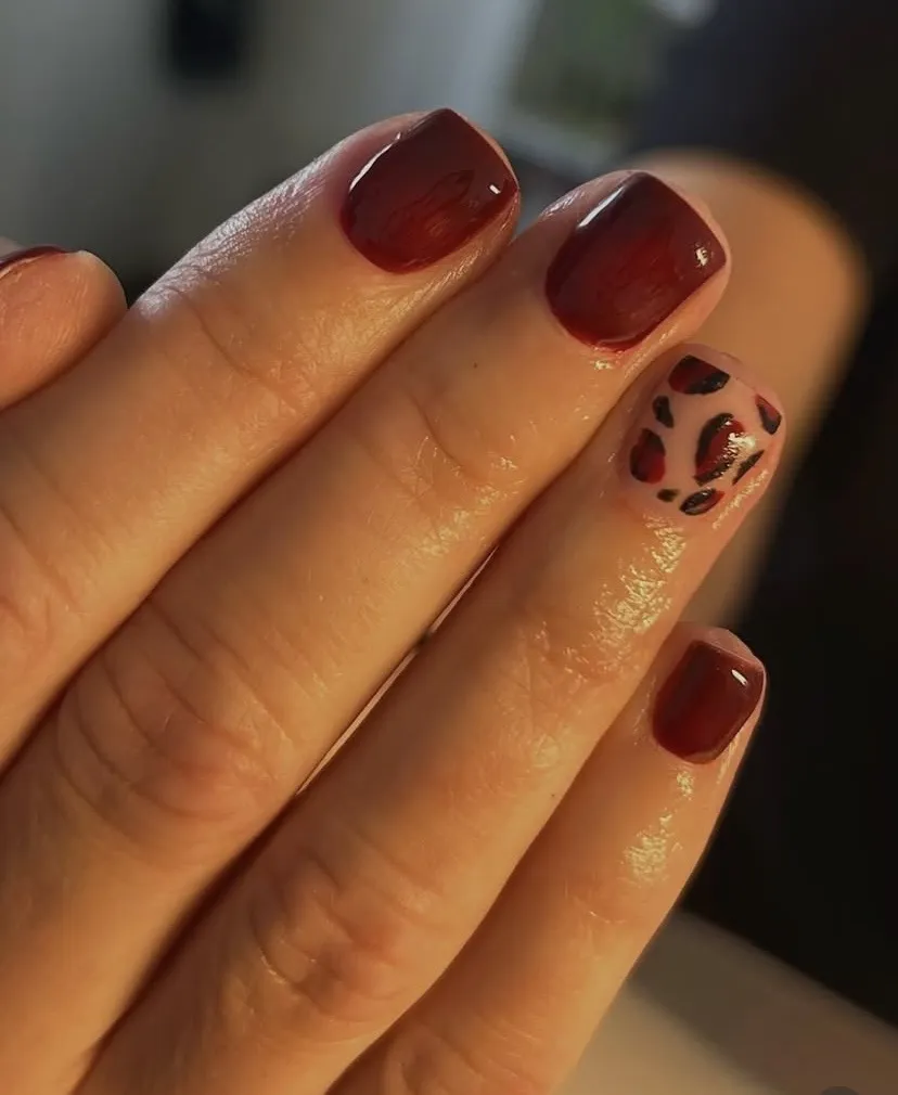 Burgundy nails with a leopard-print accent, by Beauty by Amy