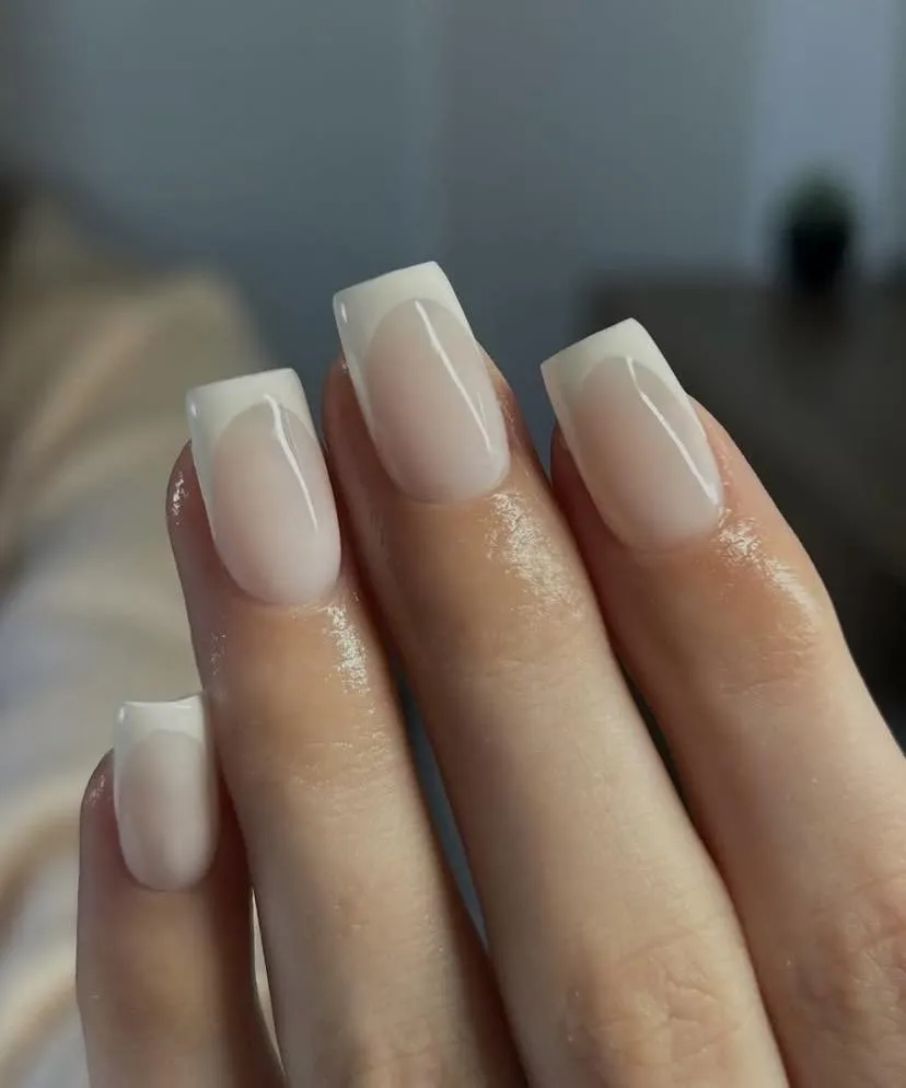 Cream French tips with a soft nude base, created by Amy