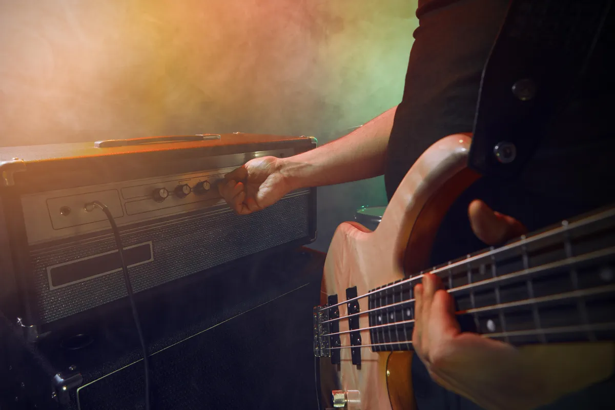 Bassist adjusting bass amp controls