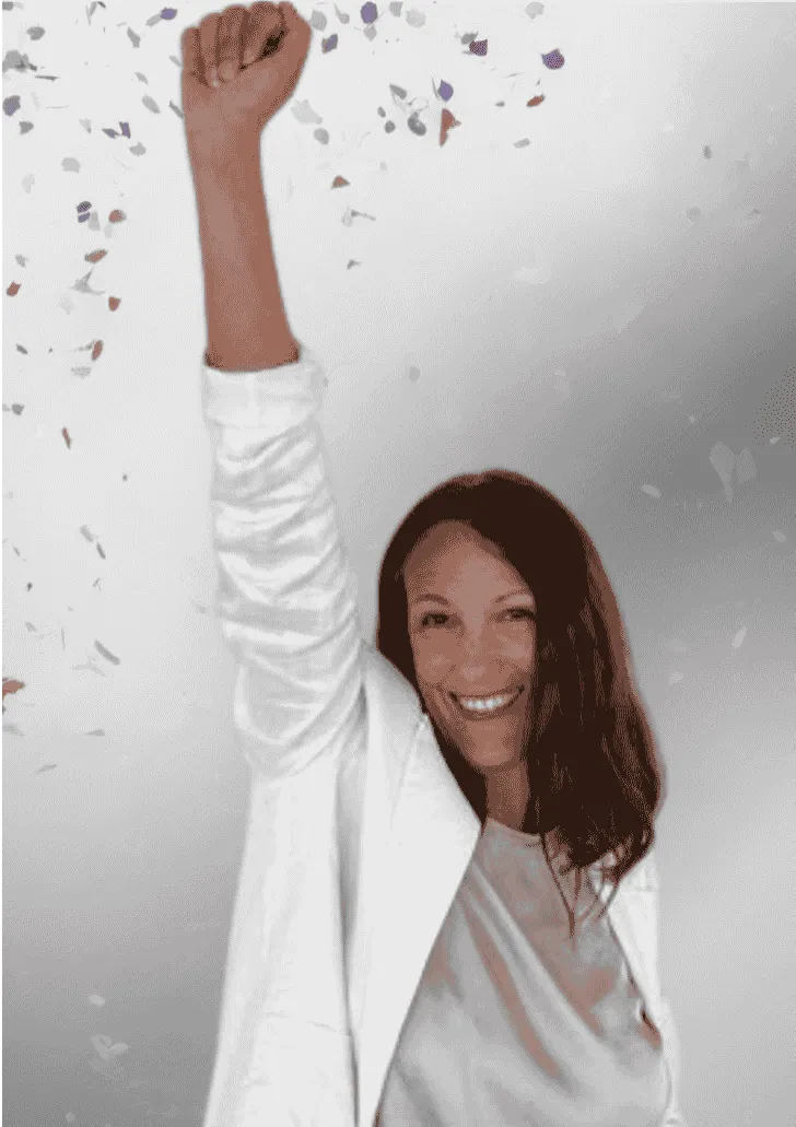 Mentalcoach m Sport Kerstin Waterman wirft Konfetti. Sie trägt einen weißen Blazer und  reckt den Arm in die Höhe. 