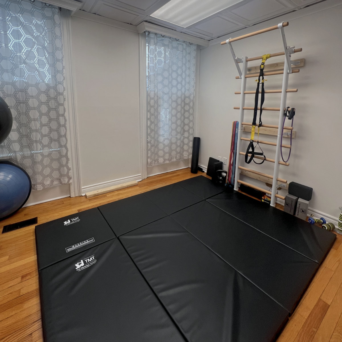 Quiet bodywork studio with padded floor mats and functional movement equipment designed for embodied, nervous-system-aware practice.