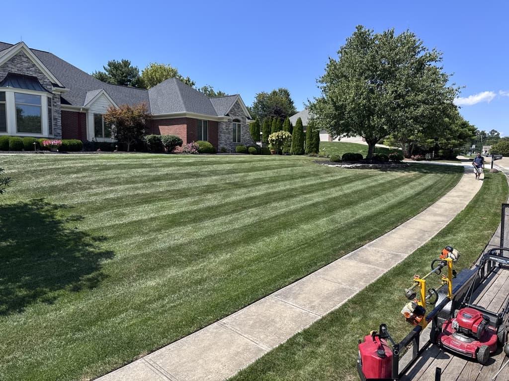 Freshly striped residential front lawn in Edgewood, Kentucky maintained by Earl’s Lawn Service with professional mowing equipment on site.