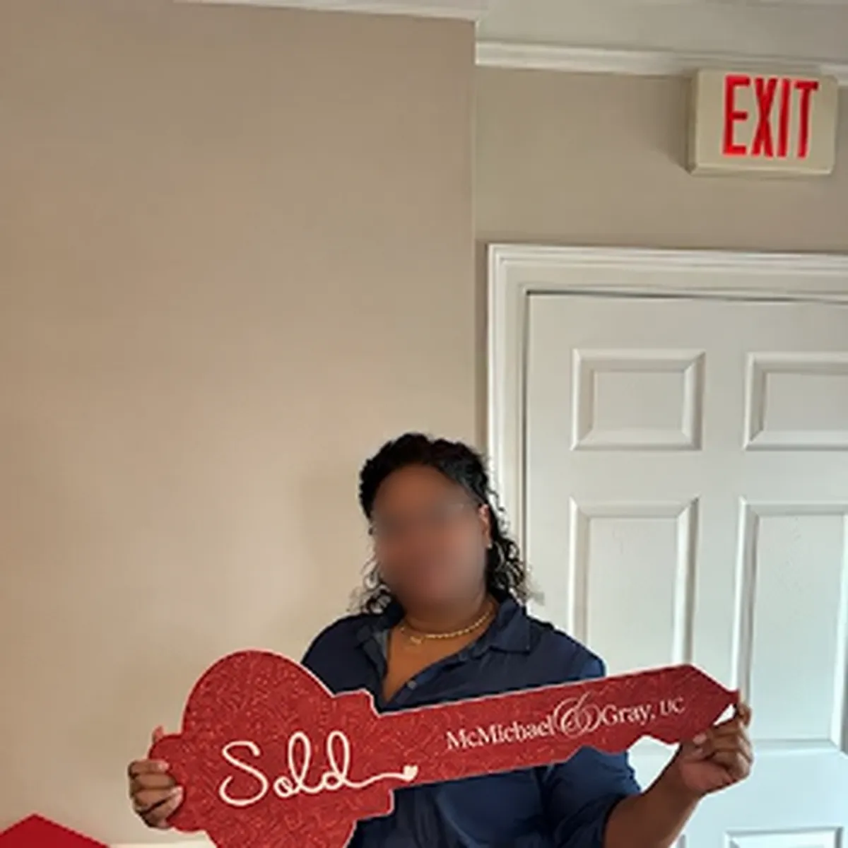 Relocation client holding a SOLD key, with her face blurred for privacy.