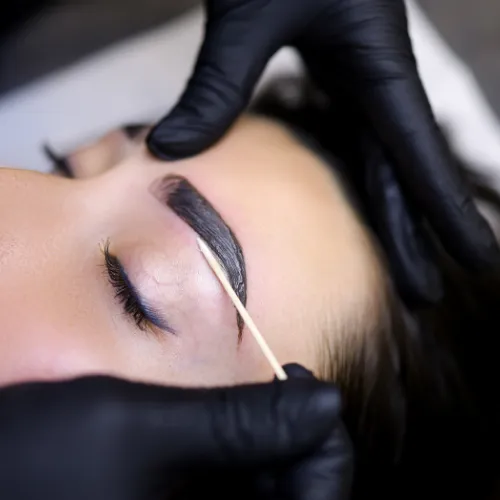 Transparente Parfümflasche mit goldener Kappe, auf cremefarbenem Stoff, mit Lichtreflexen und luxuriösem Flair. Realistische Fotografie, 1:1-Format.