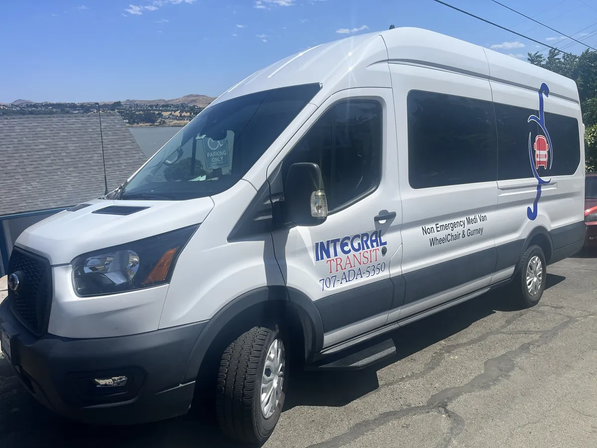 White Integral Transit Ford Transit van with the blue and red logo, labeled Non Emergency Medi Van, Wheelchair and Gurney