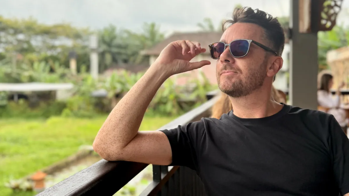 A confident and happy gay man over 50 enjoying a tropical lifestyle, representing life reinvention.