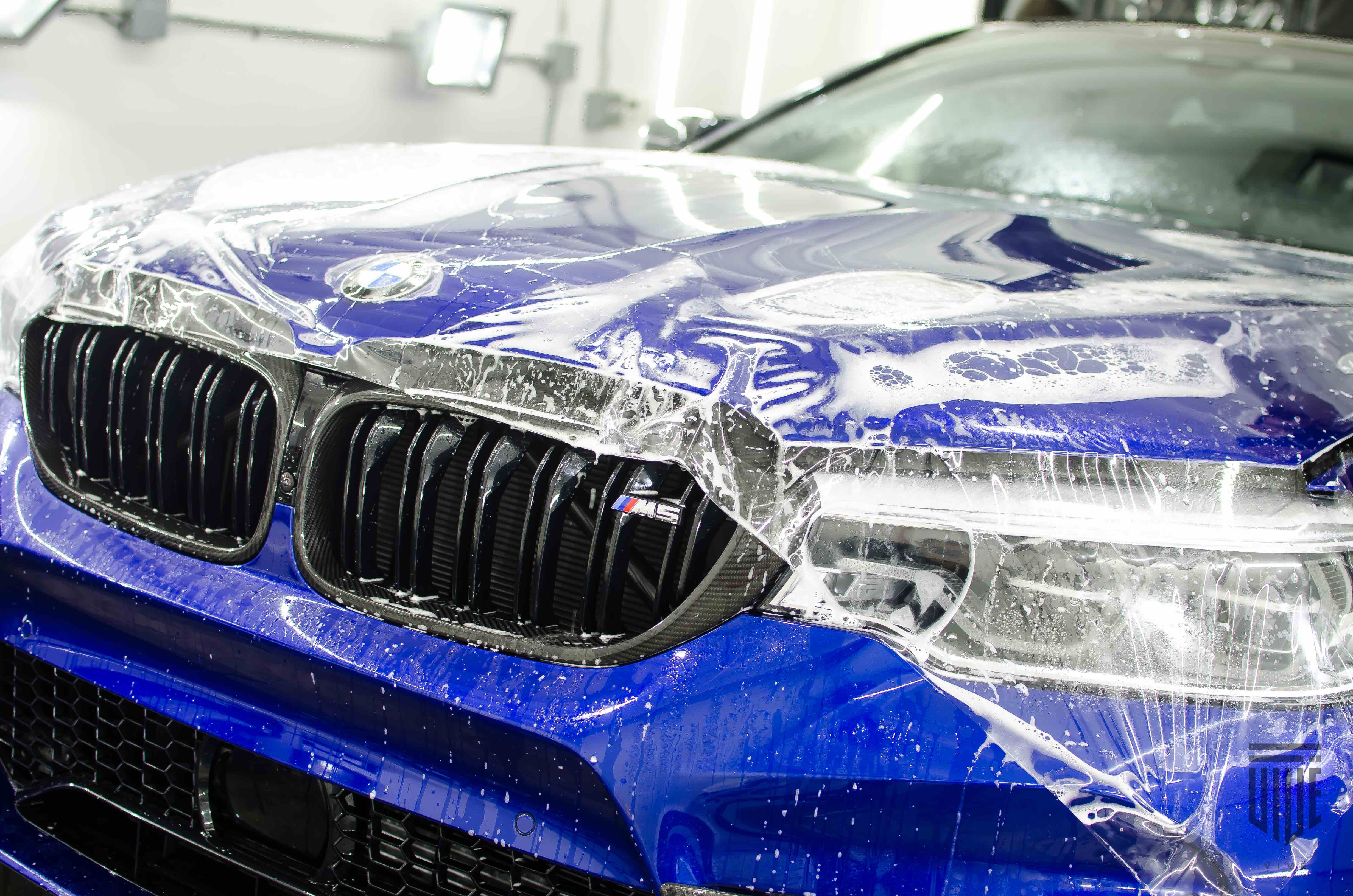 BMW vehicle with blue paint coated in Paint Protection Film (PPF), showcasing a self-healing surface and water droplets, emphasizing premium automotive detailing and protection services by VIVE Auto Styling.