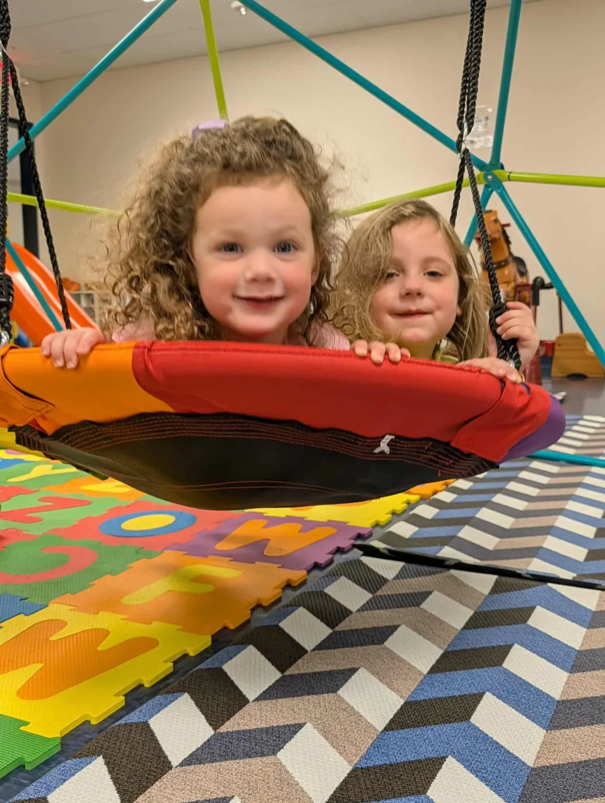 Bright, calm preschool classroom interior with low shelves of sensory materials and child-sized furniture in soft natural light.
