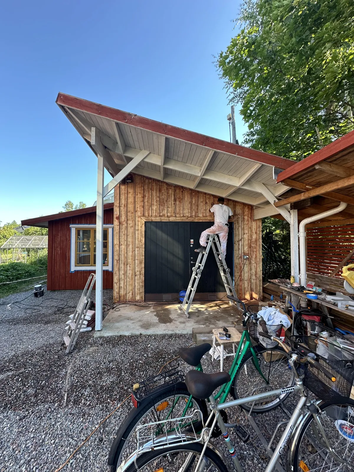 Hus och ett garage från utsidan som precis blivit målade med ljusgrå färg ch ytbehandling.