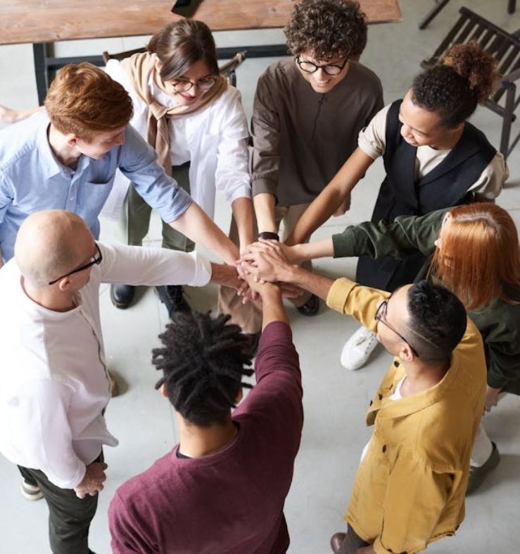 8 people in a circle with hands connected in the middle to  celebrate