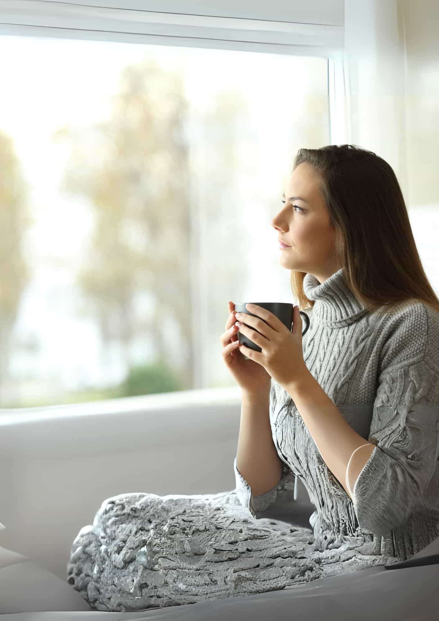 Femme pensive à un bureau lumineux, notes et ordinateur portable, lumière naturelle, ambiance contemporaine, réflexion et découverte de soi.