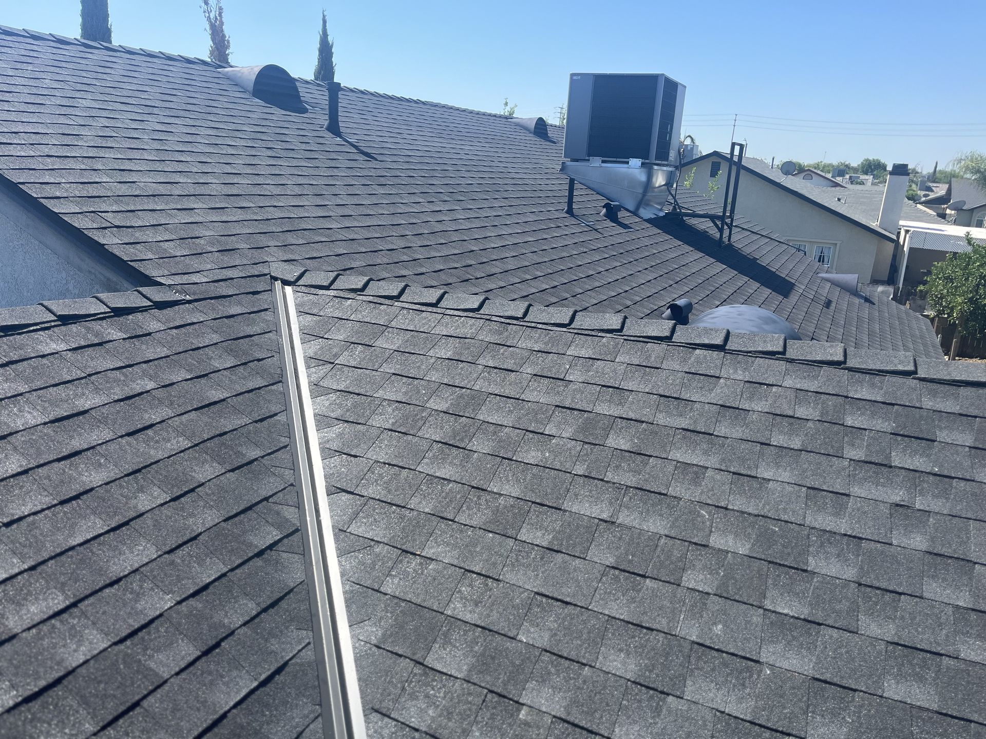Charcoal architectural shingle roof with ridge vents and a rooftop evaporative cooler