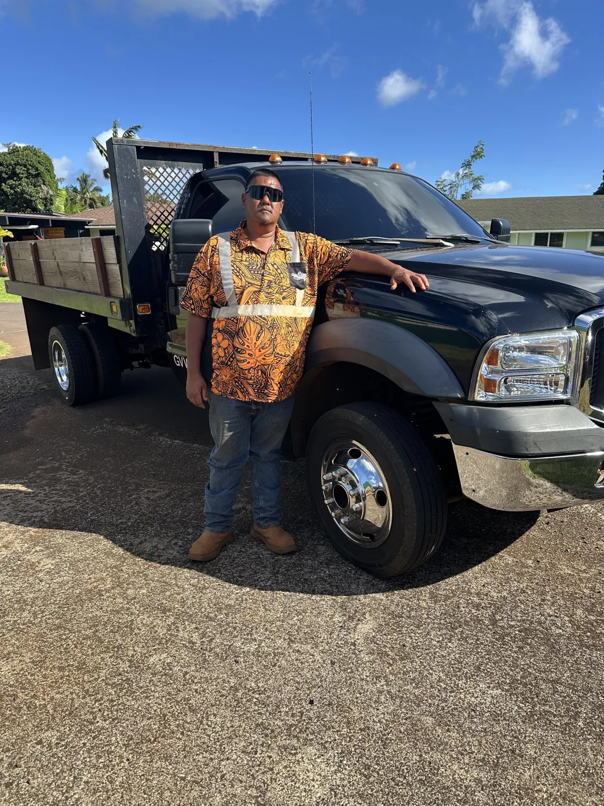 Tyson Yamashita standing next to his work truck in Kalaheo, Kauai, ready for land clearing, forestry mulching, and brush clearing services.