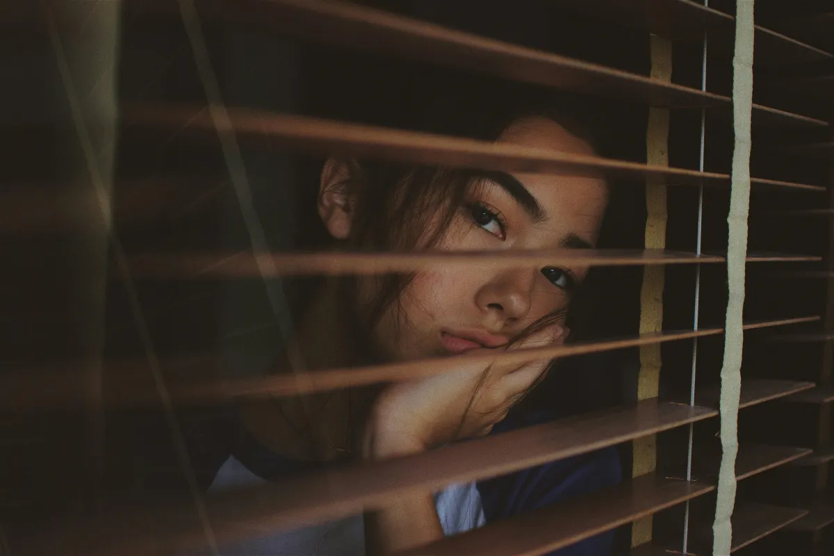 Young woman looking out window, depressed
