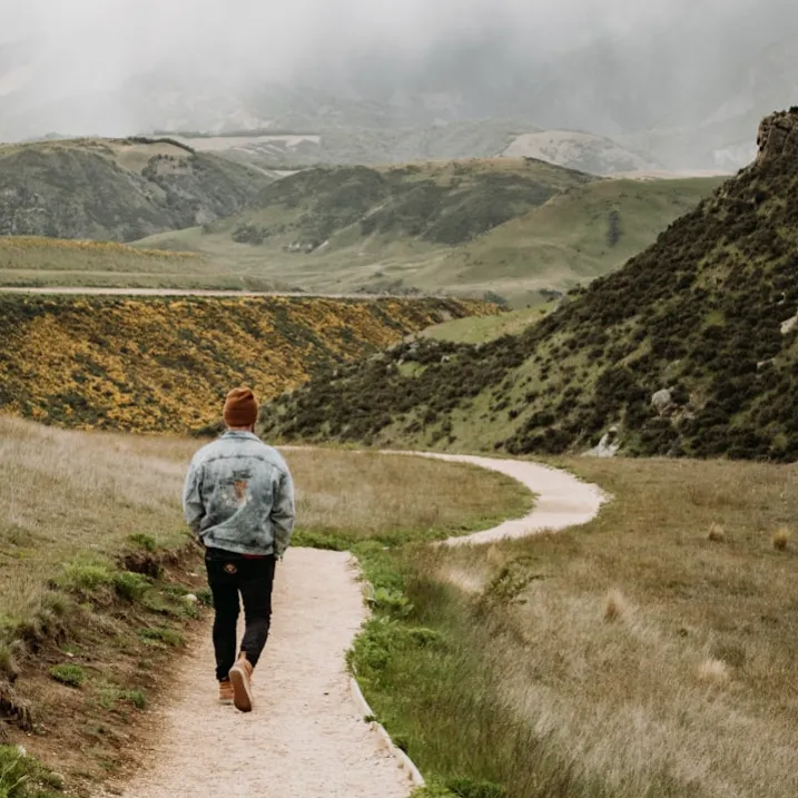 Man walking down path in picturesque mountains