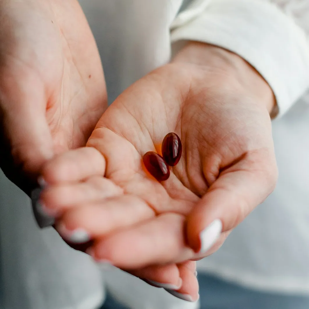 Woman's hand with 2 softgel vitamins
