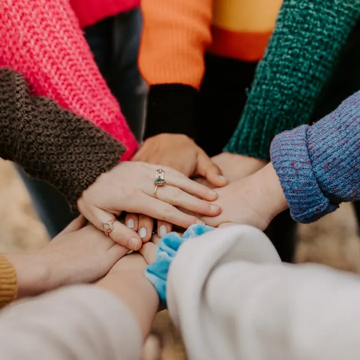 People off camera, standing in a circle, with their hands in-frame, stacked on top of each other