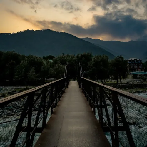 Perspective view of standing on bridge over river looking off into sunset mountains