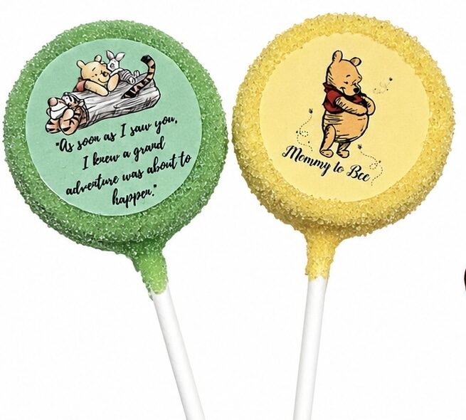 Two baby shower cake pops, one green with a storybook quote and one yellow "Mommy to Bee" design, by Sugar Coast Sweets